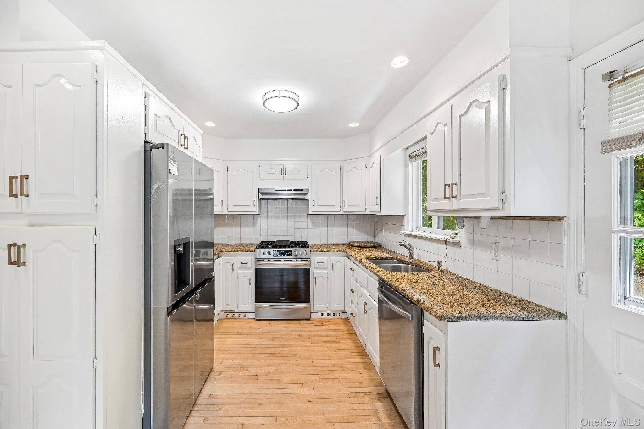 10 River Road Scarsdale, NY 10583 - Photo 11 of 20 Kitchen featuring stainless steel appliances, backsplash, light wood-style flooring, white cabinetry, and recessed lighting