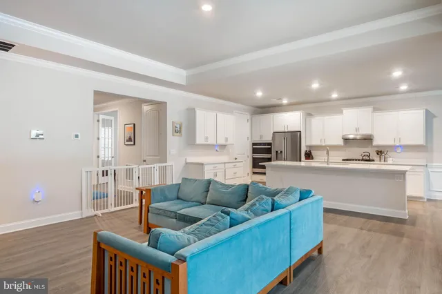 a living room with furniture and kitchen view with wooden floor