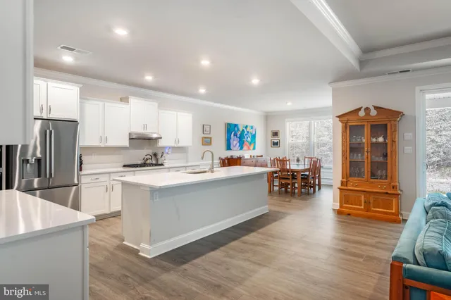 a kitchen with stainless steel appliances a refrigerator a stove top oven and a dining table with wooden floor