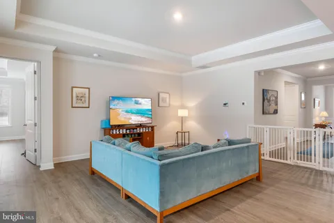 a living room with furniture and kitchen view with wooden floor