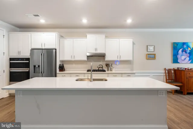 a large kitchen with stainless steel appliances granite countertop a stove a sink a refrigerator and white cabinets granite countertops with wooden floor