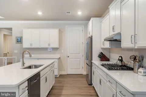 a kitchen with a sink a stove cabinets and wooden floor