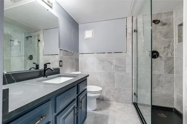 a bathroom with a granite countertop sink a toilet and shower
