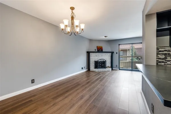 an empty room with wooden floor fireplace and windows