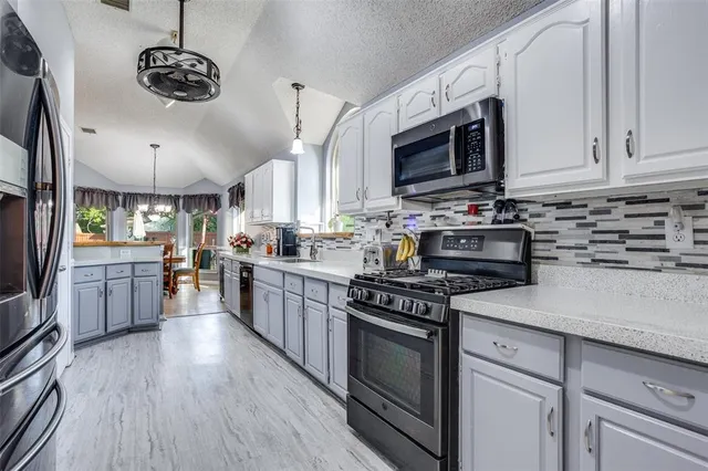 a kitchen with stainless steel appliances granite countertop a stove a sink dishwasher and a microwave oven with wooden floor