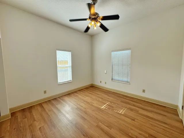 a view of empty room with wooden floor and fan