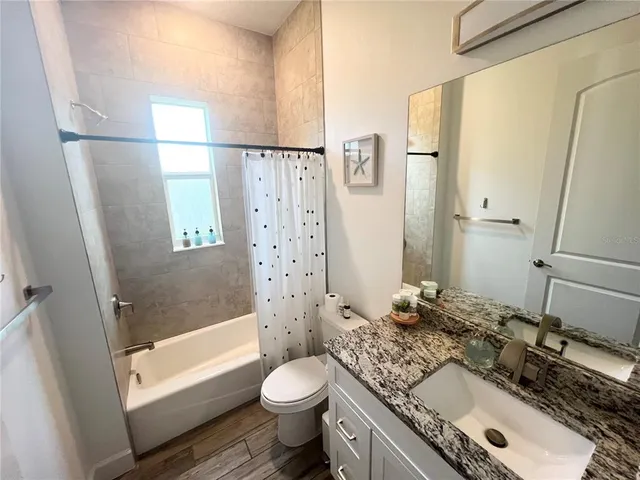 a bathroom with a granite countertop sink toilet and shower