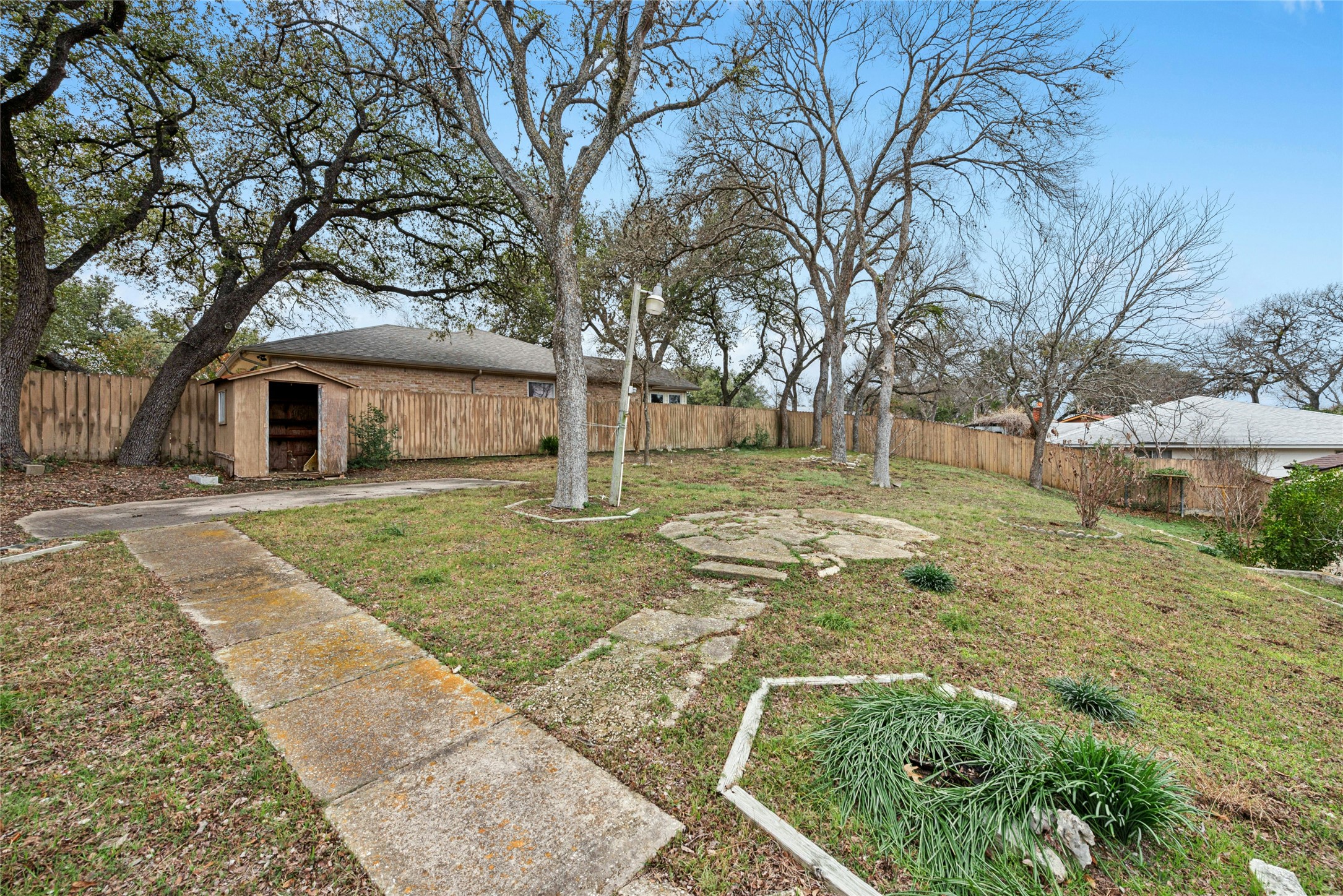 1444 Salem Meadow Circle Austin, TX 78745 - Photo 33 of 35 a view of a white house with a yard covered with plants and large trees