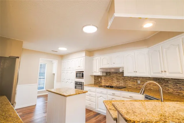 a kitchen with stainless steel appliances granite countertop a refrigerator and a stove top oven