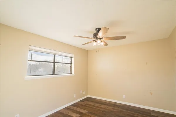 an empty room with wooden floor fan and windows