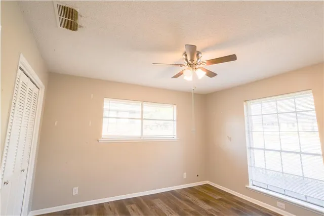 an empty room with wooden floor and windows