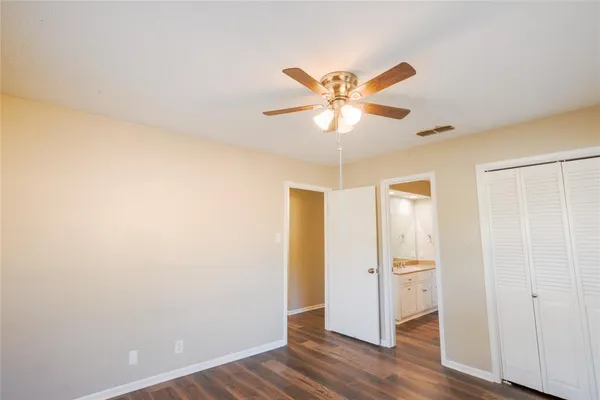an empty room with wooden floor and a ceiling fan