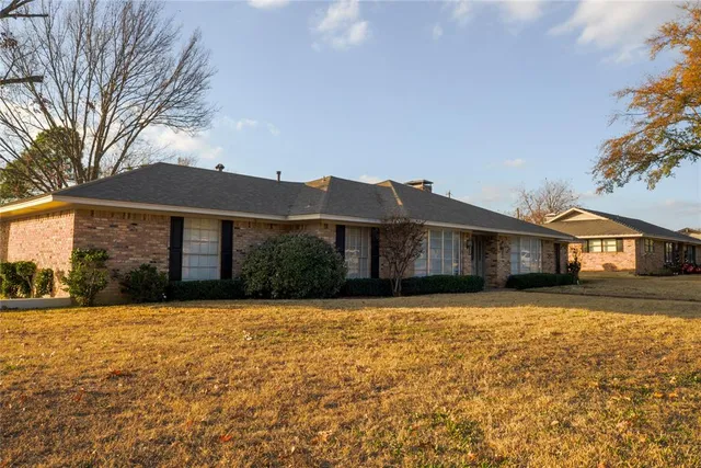 a front view of a house with a yard covered with trees