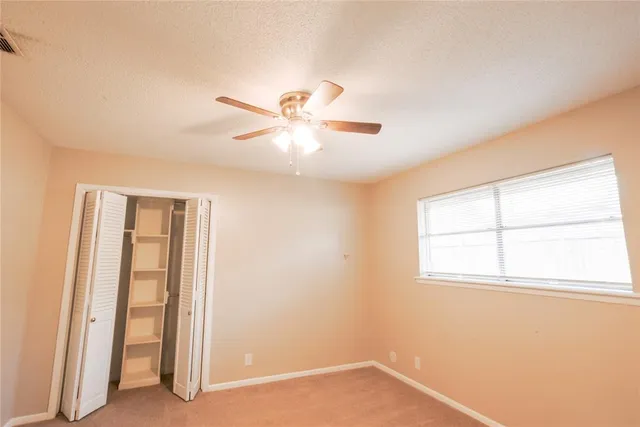 an empty room with a window and a ceiling fan