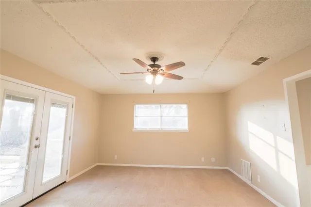 an empty room with windows and fan
