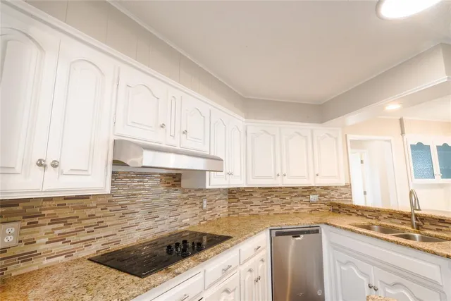 a kitchen with granite countertop a sink a stove and cabinets