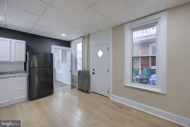 a view of a kitchen with refrigerator and wooden floor