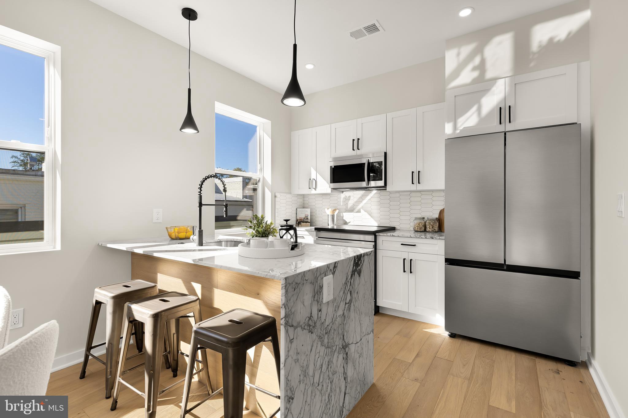2606 41st Street Northwest, Unit PH Washington, DC 20007 - Photo 7 of 29 a kitchen with stainless steel appliances granite countertop a refrigerator a sink dishwasher a stove and a refrigerator with wooden floor