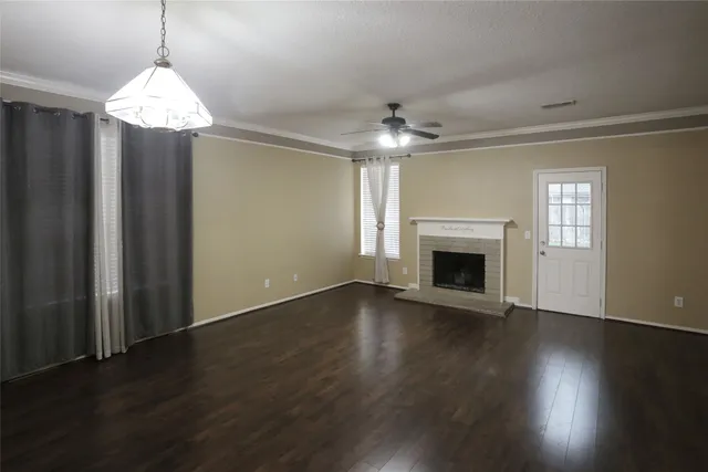 an empty room with wooden floor fireplace and windows
