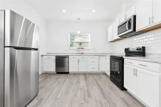a kitchen with white cabinets and stainless steel appliances