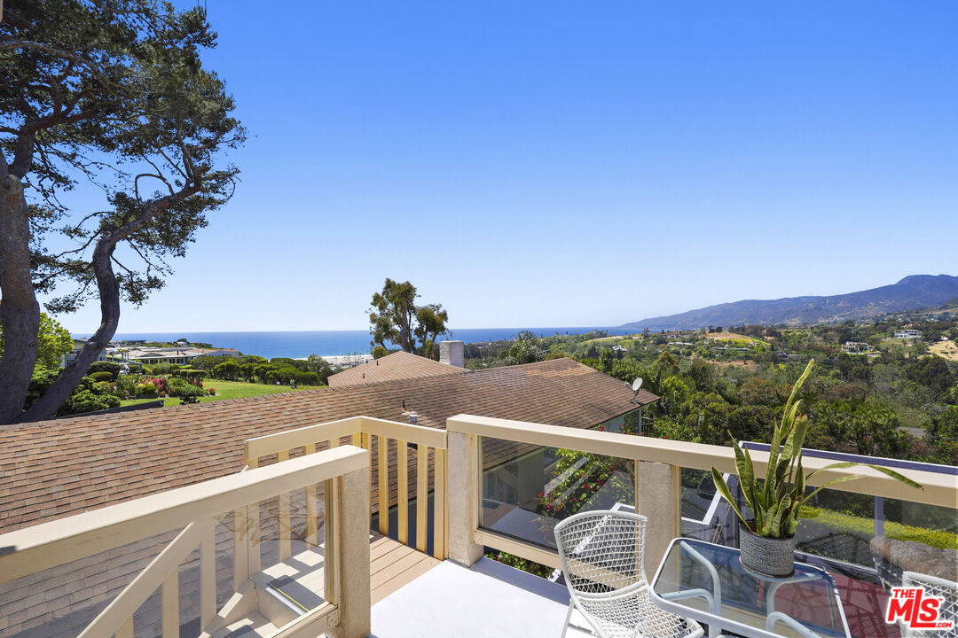 29355 Heathercliff Road, Unit GUESTHOUSE Malibu, CA 90265 - Photo 3 of 26 a view of a balcony with wooden chairs and floor to ceiling window