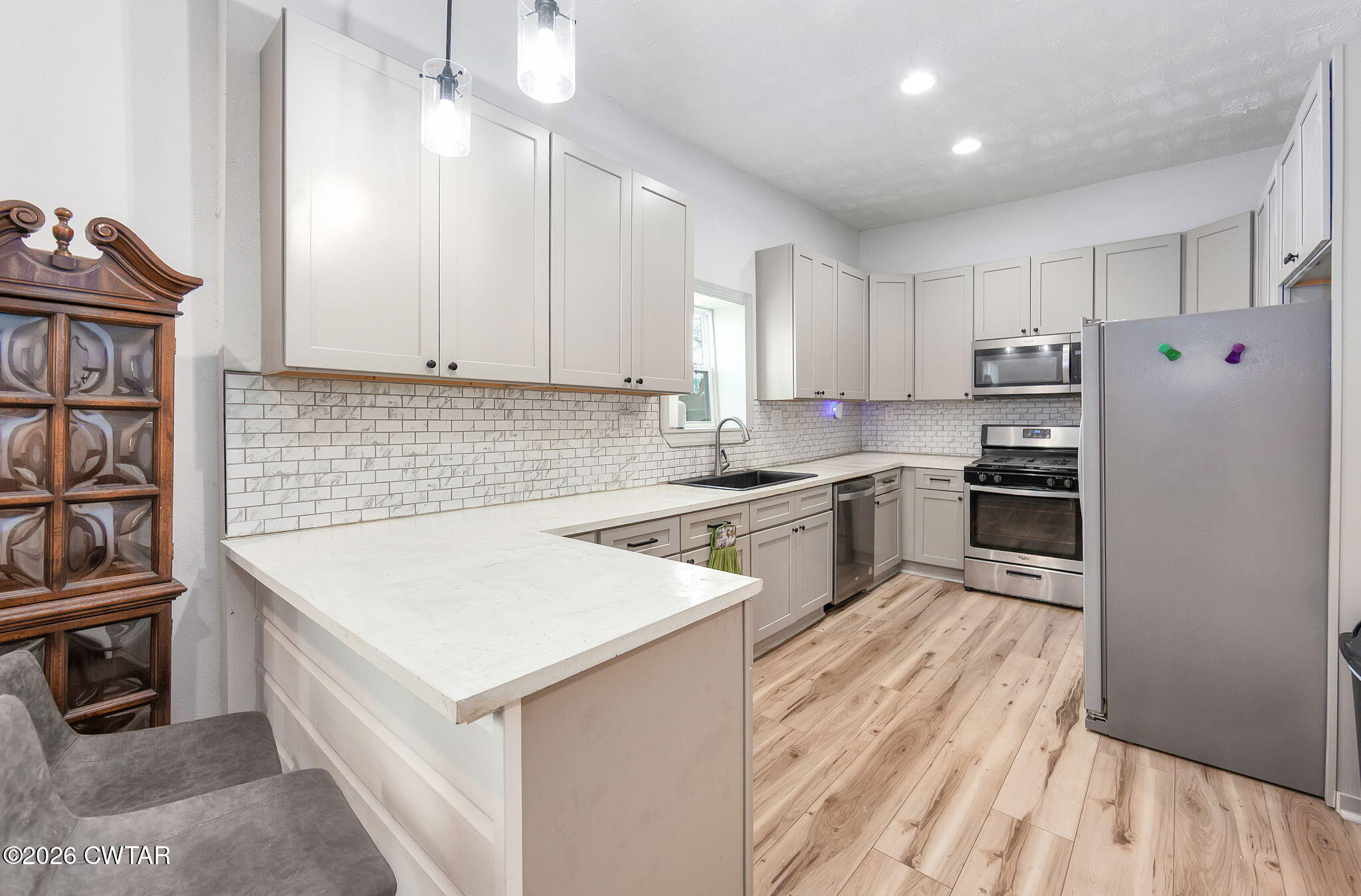 209 Hatton Street Jackson, TN 38301 - Photo 6 of 20 a kitchen with kitchen island a sink dishwasher stove and white cabinets with wooden floor