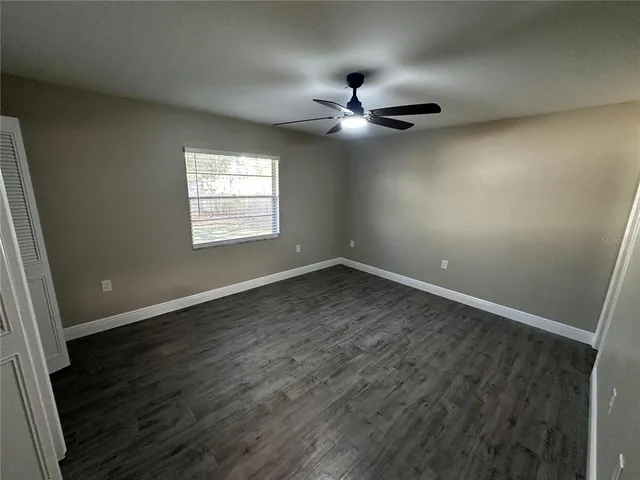 an empty room with wooden floor fan and windows