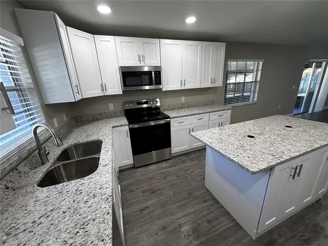 a kitchen with stainless steel appliances kitchen island granite countertop a sink stove and microwave