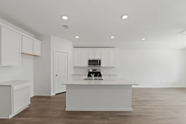 a view of kitchen with kitchen island stainless steel appliances a sink and a stove