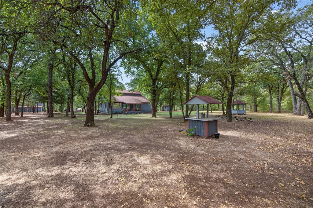 10964 River Ranch Road Kemp, TX 75143 - Photo 2 of 40 Extensive tree coverage, multiple outbuildings, well structure, and a main residence with a covered porch