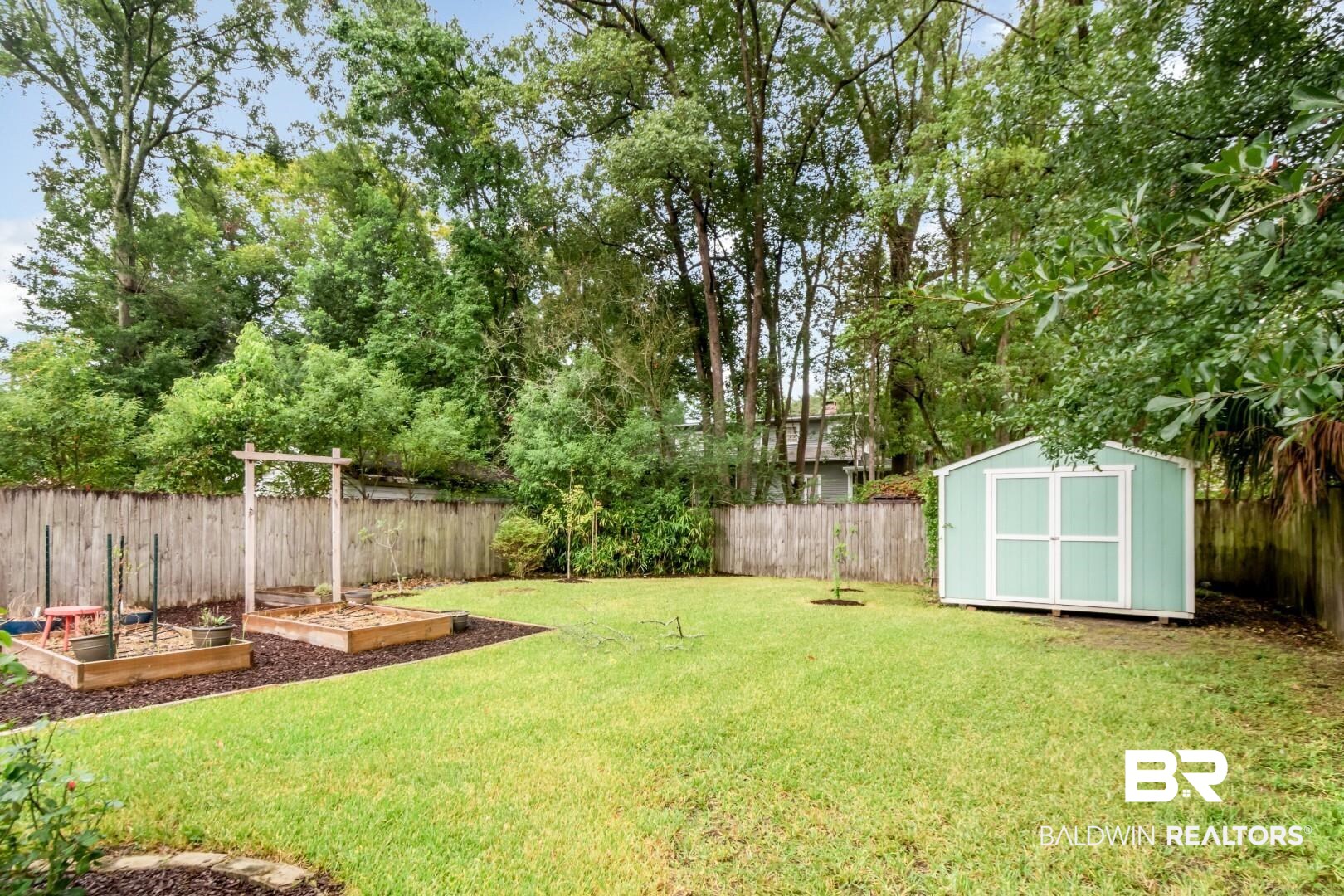 14 Kenneth Street Mobile, AL 36607 - Photo 27 of 32 Fenced backyard featuring a garden and a storage unit