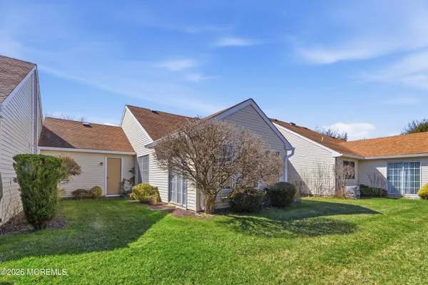 a view of a house with a big yard potted plants and large tree