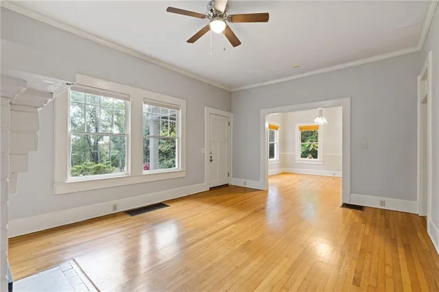 a view of an empty room with wooden floor and a window