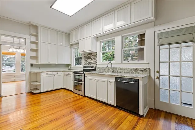 a kitchen with granite countertop wooden floors stainless steel appliances and sink