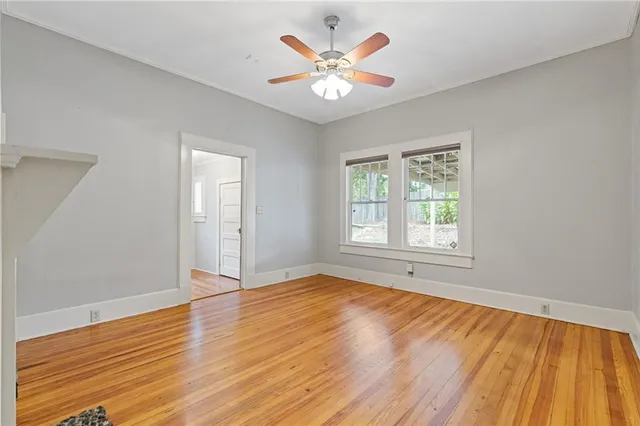 a view of an empty room with wooden floor and a window