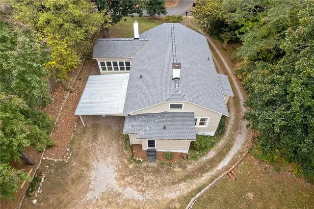 an aerial view of a house with a yard and covered with trees
