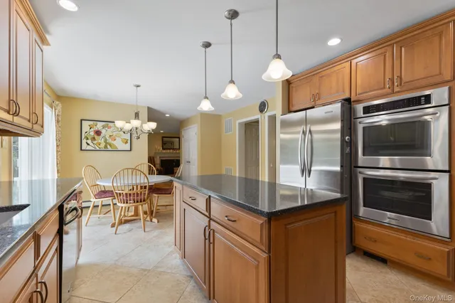 a kitchen with stainless steel appliances granite countertop a stove a sink a refrigerator and a wooden cabinets