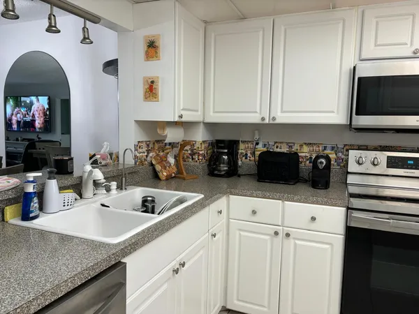 a kitchen with white cabinets and sink