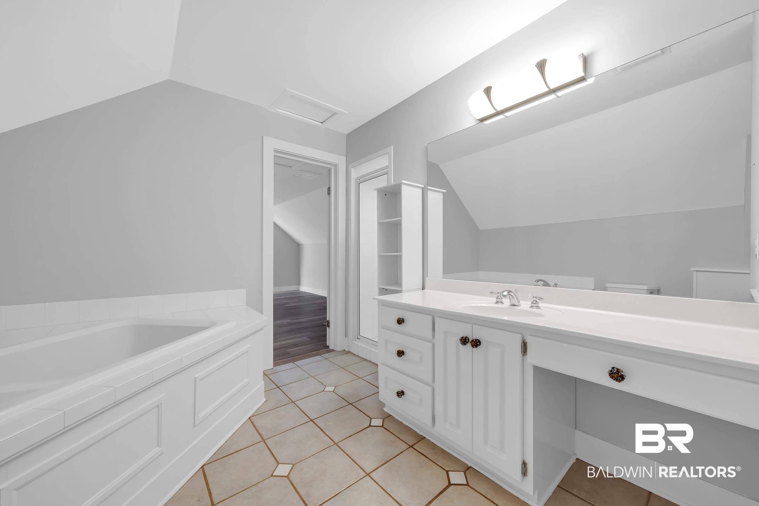 43199 Pine Grove Road Bay Minette, AL 36507 - Photo 63 of 71 Bathroom featuring a built-in tub with tile surround, a spacious vanity with an integrated sink, broad wall-mounted mirror, and tile flooring