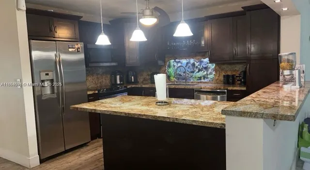 a kitchen with kitchen island granite countertop stainless steel appliances lots of counter top space cabinets and furniture