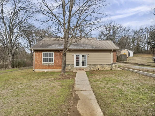 a backyard of a house with large trees and barbeque oven
