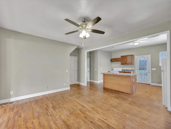a view of an empty room with window and wooden floor