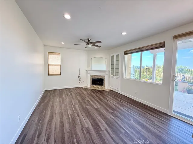 an empty room with windows a fireplace and wooden floor