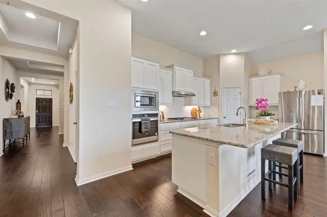a kitchen with stainless steel appliances granite countertop a table chairs sink and cabinets
