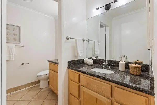 a bathroom with a granite countertop sink a toilet and a mirror