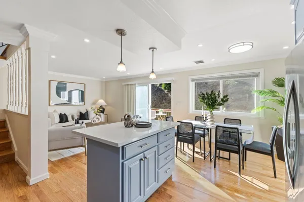 a open kitchen with stainless steel appliances granite countertop a stove top oven a dining table and chairs with wooden floor