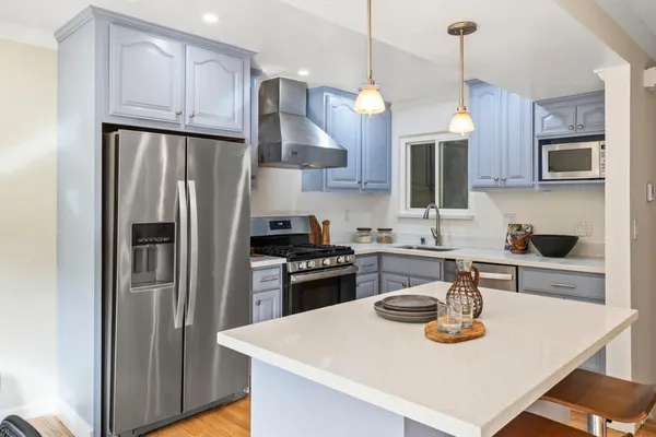 a kitchen with stainless steel appliances granite countertop a sink a stove a refrigerator and cabinets