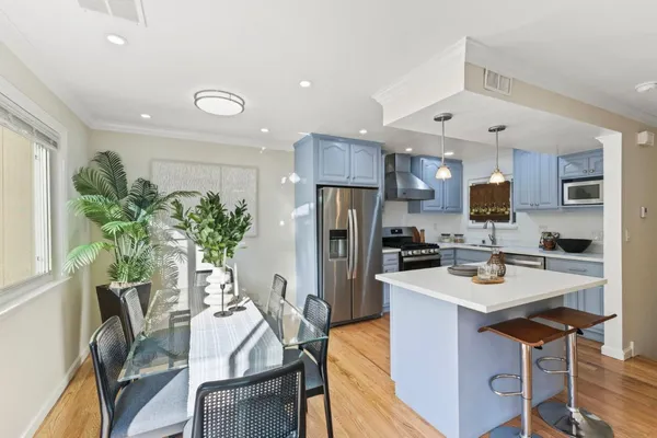 a kitchen with stainless steel appliances a dining table chairs stove and refrigerator