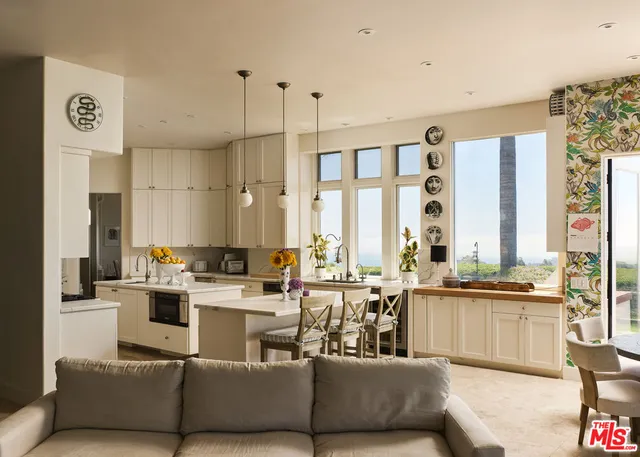 a living room with furniture kitchen area and a large window
