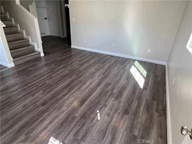 a view of an empty room with wooden floor and stairs